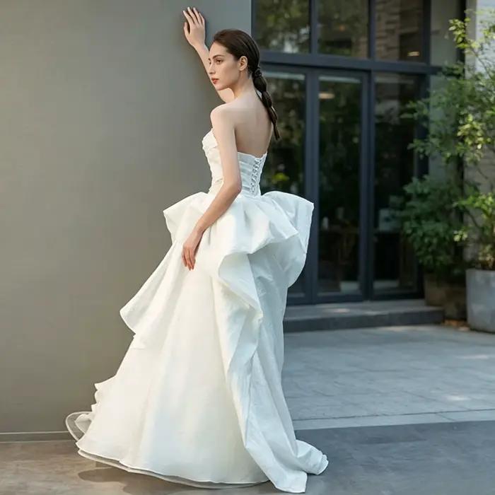 Robe de mariée moderne personnalisée asymétrique en organza coupe trapèze avec grand nœud et volants en cascade pour réception nuptiale et défilé de mode