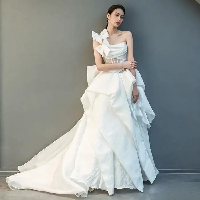 Robe de mariée moderne personnalisée asymétrique en organza coupe trapèze avec grand nœud et volants